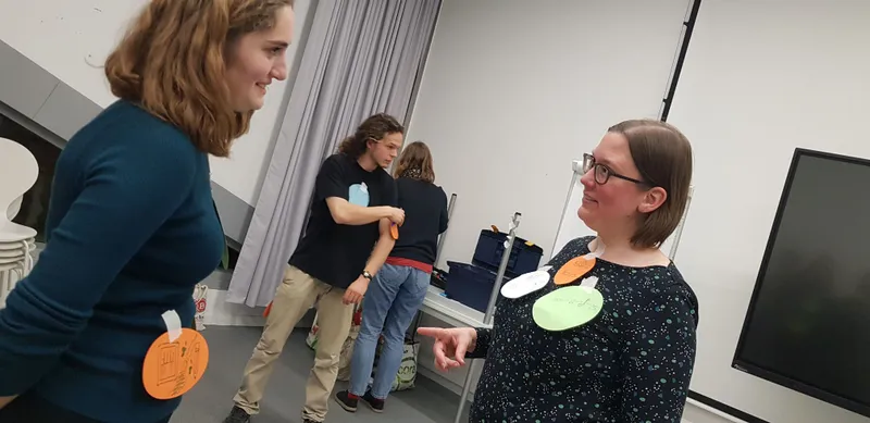 Ein Mann in Anzug und Krawatte sitzt auf einem Stuhl und lächelt in die Kamera. Er hält einen Joint in der Hand und macht eine Geste mit der anderen Hand. Er...
