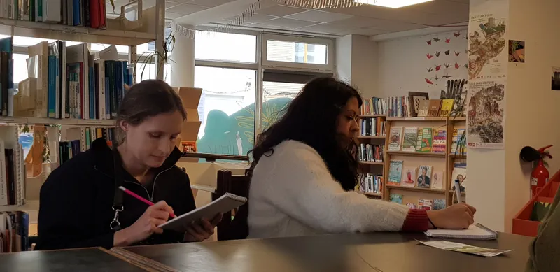 Ein Büro mit einem Schreibtisch, einem Bücherregal und Regalen, gefüllt mit Büchern und Publikationen. Der Raum ist mit einem modernen Interieur ausgestattet...