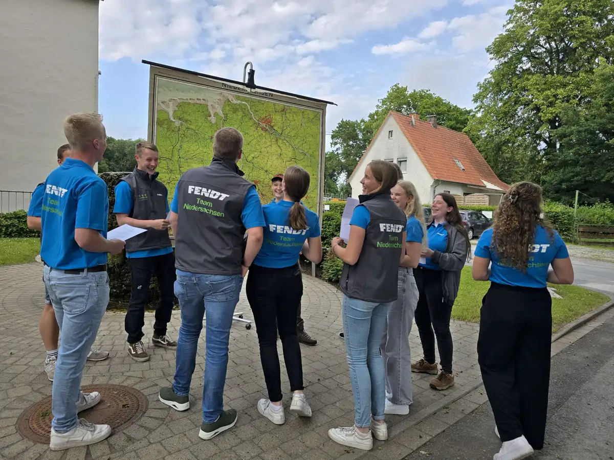 Eine Gruppe junger Menschen von Team Niedersachsen stehen lachend vor einer Karte
