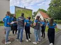 Eine Gruppe junger Menschen von Team Niedersachsen stehen lachend vor einer Karte