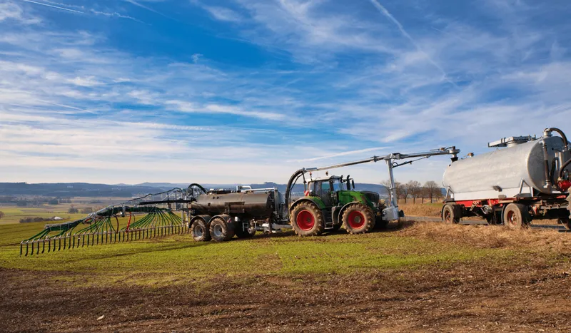 Ein Traktor wird unter freiem Himmel für das Ausbringen von Dünger vorbereitet.