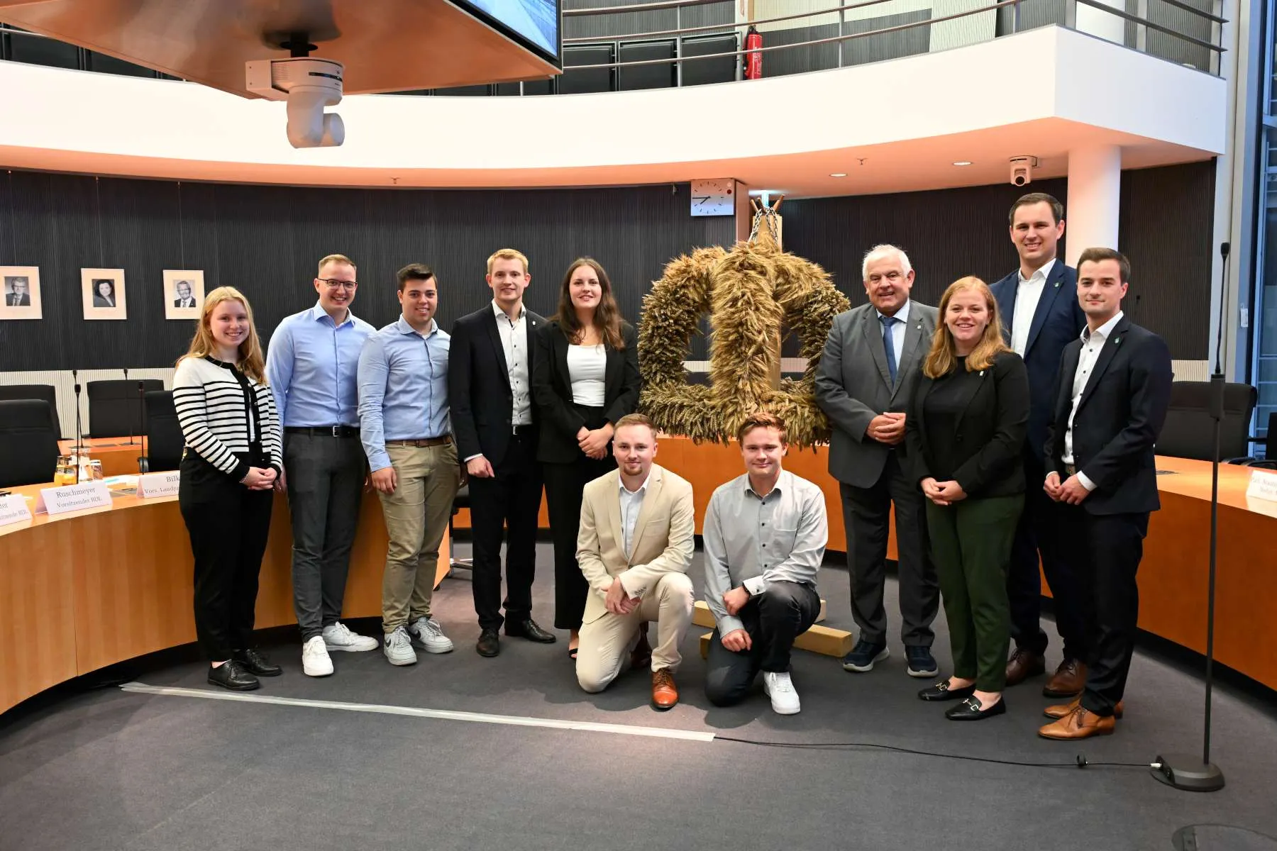 Eine Gruppe Junger Menschen posiert im Ausschuss Saal mit einer Erntekrone