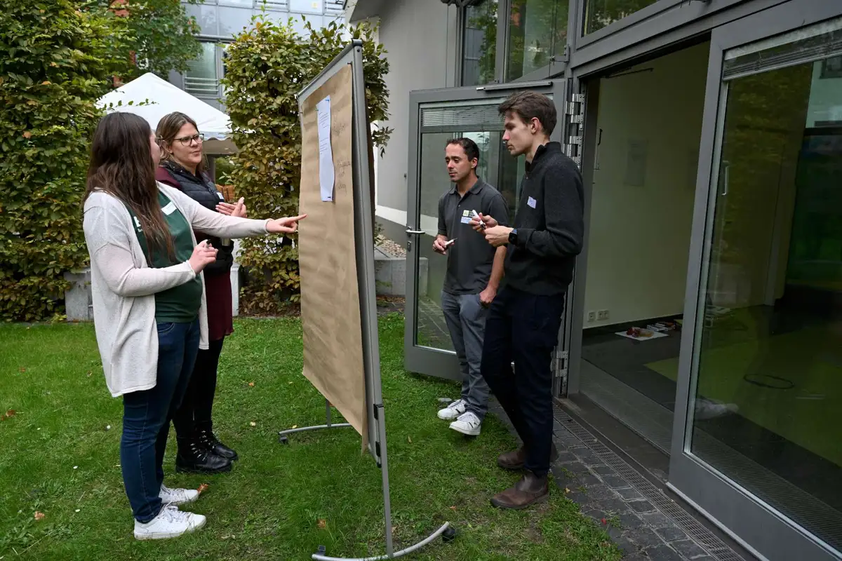 Vier junge Menschen arbeiten an einem pinboard