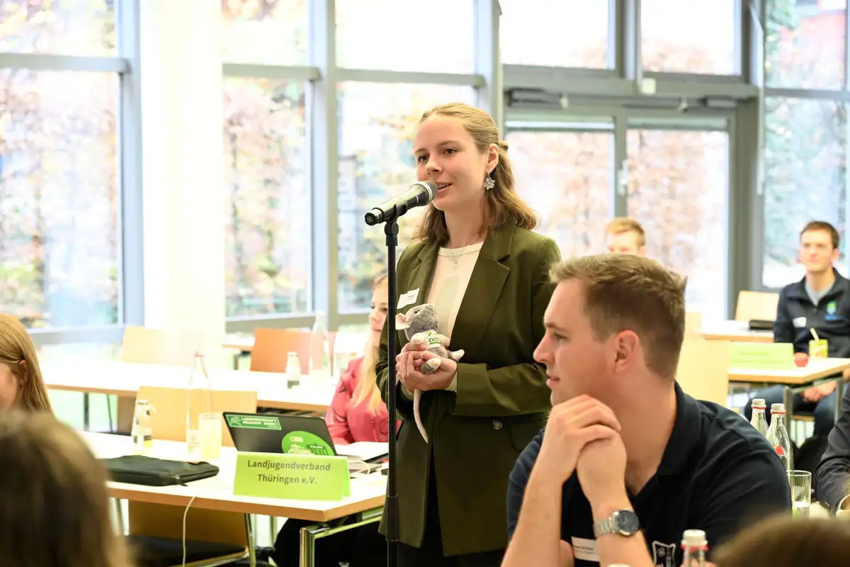 Teilnehmerin spricht am Mikrofon mit Plüschratte