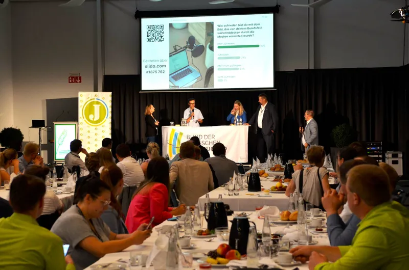 Junglandwirtinnen beim Deutschen Bauerntag in Cottbus. Sie sitzen an einem gedeckten Tisch mit Wein und genießen die Gesellschaft und den Austausch. 

