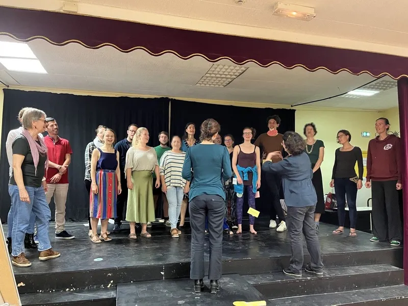 Ein Team von Performern in Jeans posiert auf einer Bühne mit Bühnenausrüstung. Sie tragen trendige Denim-Outfits und wirken entspannt und unterhaltsam. Ein S...