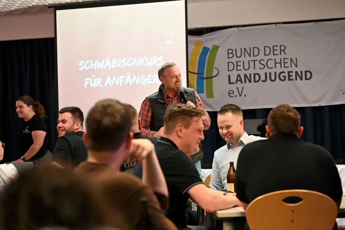 Ein Lächelnder Mann präsentiert einen "Schwäbischkurs für Anfänger"