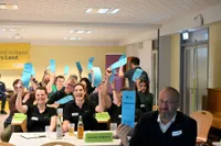 Landjugendliche lachen während sie Stimmkarten in die Luft halten