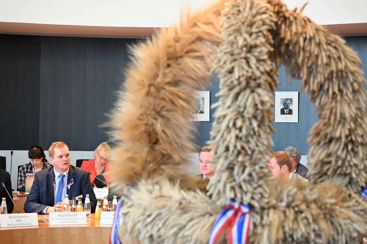 Landjugend mit Schleswig-Holsteiner Erntekrone und dem Vorsitzenden des LEH-Bundestagsausschusses im Sitzungssaal.