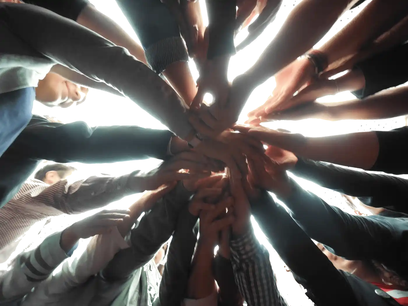 Eine große Gruppe von Menschen steht unter einem Nachthimmel mit Feuerwerk und hält ihre Hände in der Mitte zusammen. Sie feiern ein Fest und genießen die ge...