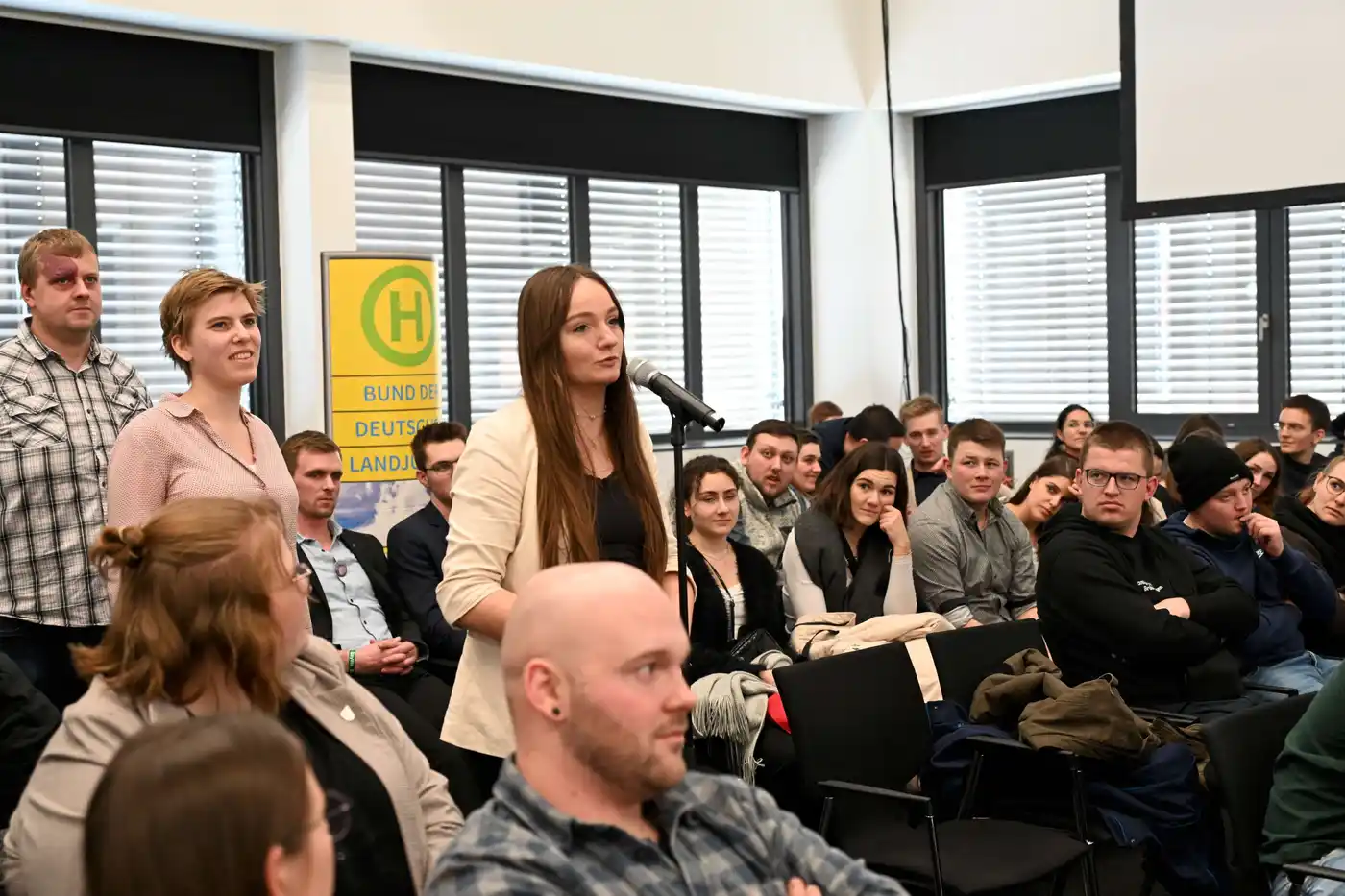 Junglandwirte und -landwirtinnen auf dem Kongress der Grünen Woche in Berlin. Sie tragen formelle Kleidung und diskutieren ihre Zukunft in der Landwirtschaft...