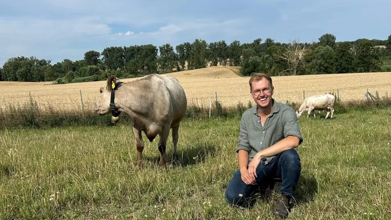 Junglandwirt Klanhämmer sitzt neben einer seiner Kühen