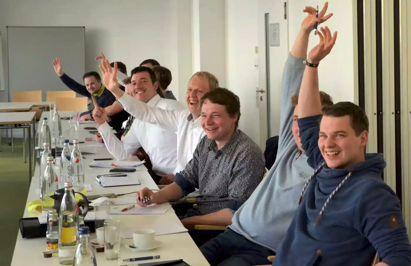 Junge Landwirte treffen sich im Arbeitskreis zu einer Diskussion an einem Tisch. Sie sitzen auf Stühlen, gestikulieren und sprechen über landwirtschaftliche ...