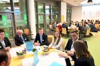 Ein großer Raum mit Personen an großen Gruppentischen