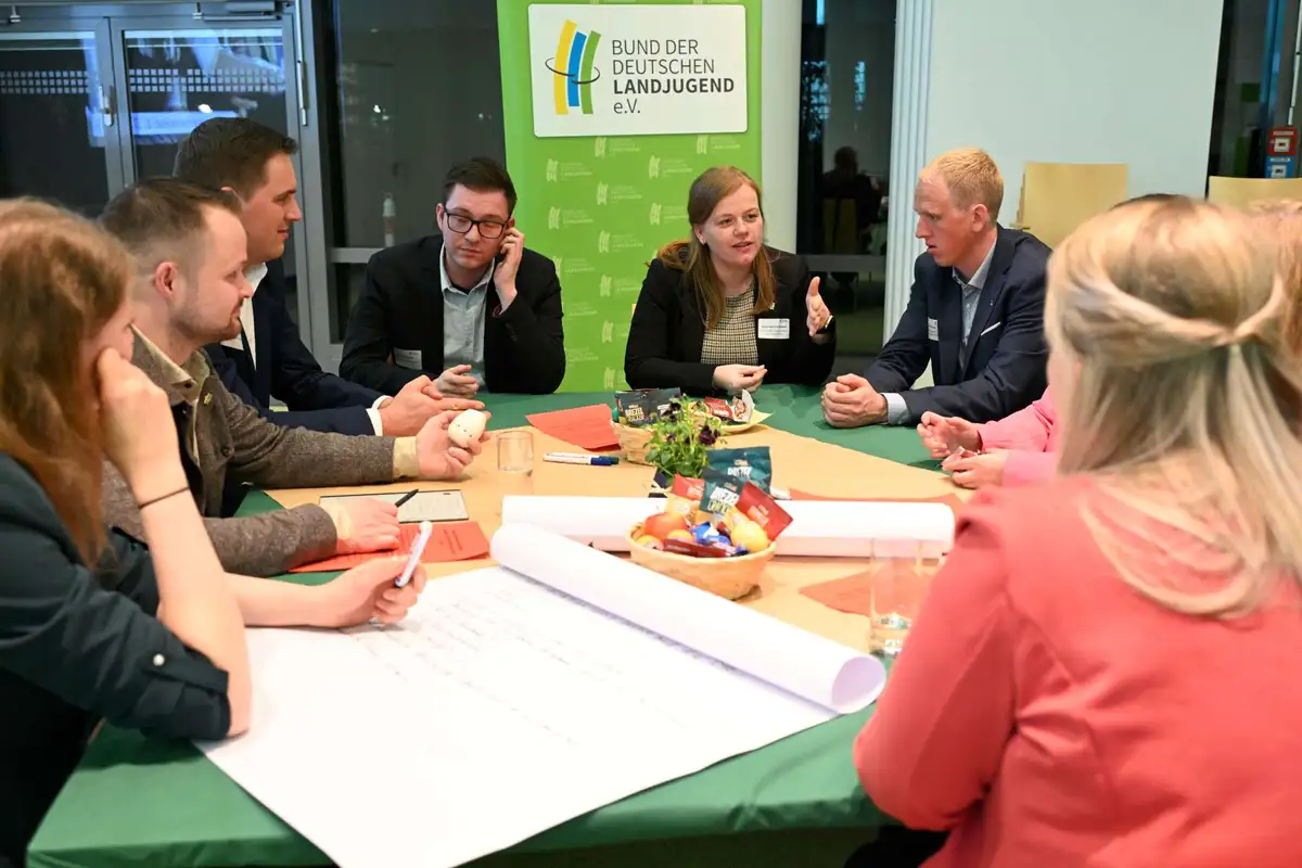 Junge Menschen diskutieren in einer Tischrunde