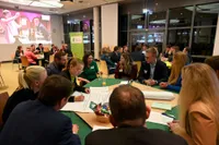Drei Gruppentische an denen diskutiert und ein Poster beschriftet wird