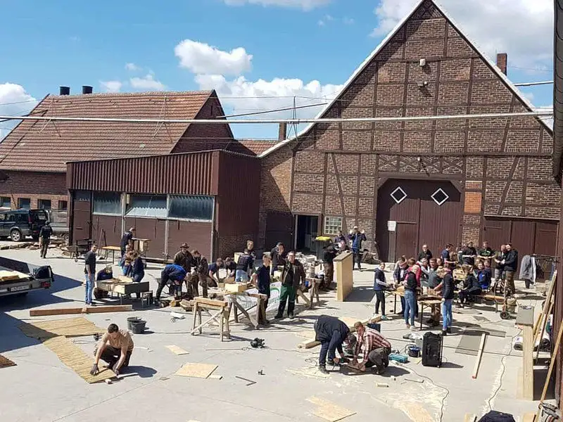 Ein modernes Gebäude mit einem begrünten Dach in einer städtischen Umgebung. Der Himmel ist bedeckt mit Wolken und spendet Schatten über den öffentlichen Pla...