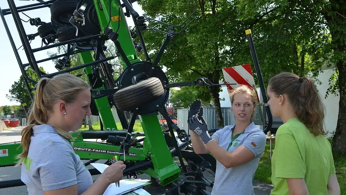 Junge Landwirtinnen an einem landwirtschaftlichen Großgerät