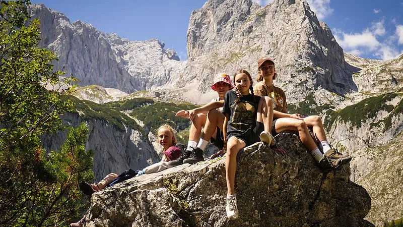 Zwei glückliche Menschen in kurzen Hosen und Sonnenbrillen genießen eine Tandemfahrt in den Bergen. Sie fahren über felsigen Untergrund mit Blick auf den bla...